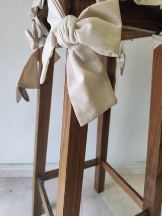 Taburete alto con cojín beige y lazos