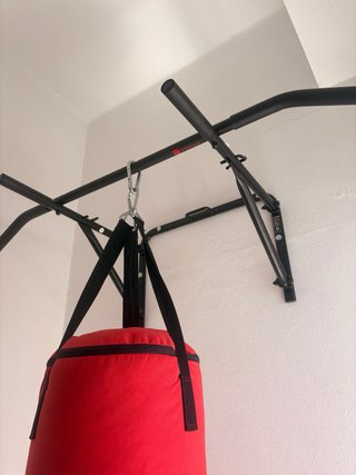 Saco de boxeo rojo con barra de dominadas.