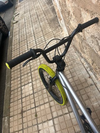 Bicicleta BMX plateada con ruedas amarillas