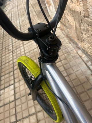 Bicicleta BMX plateada con ruedas amarillas