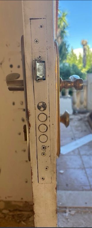 Puerta blanca con aldaba y pomo dorado