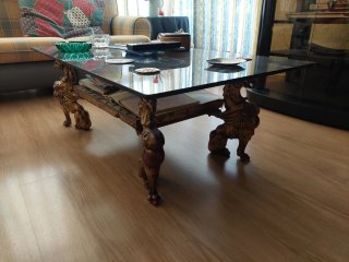 Mesa de centro dorada con tapa de cristal.