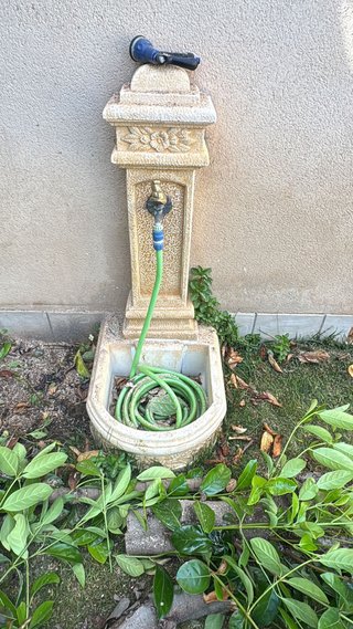 Fuente de piedra para jardín con manguera
