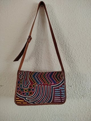 Bolso artesanal multicolor con correa de cuero.