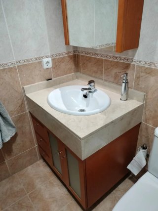 Mueble de baño con lavabo, encimera y grifería.