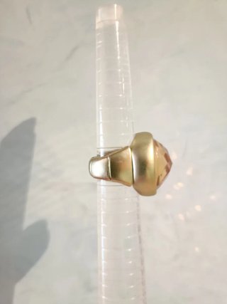 Anillo extensible dorado con piedra naranja/ámbar.