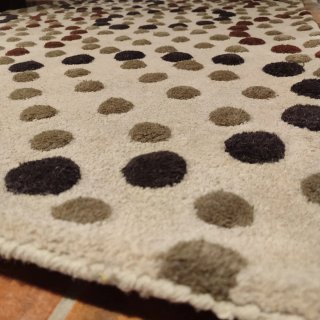 Alfombra beige con lunares marrones.