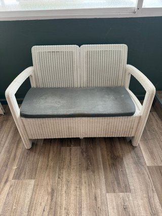 Sofá de mimbre blanco con cojín gris