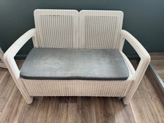 Sofá de mimbre blanco con cojín gris