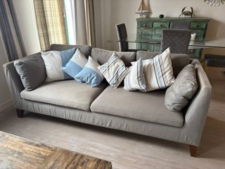 Sofá de tela gris con patas de madera.