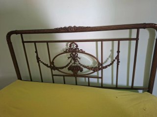 Cama antigua de bronce con detalles ornamentales