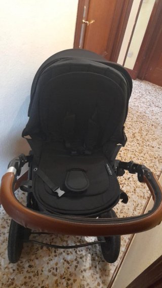 Carro de bebé negro con plástico de lluvia
