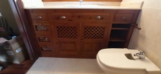 Mueble de baño de madera y mármol con gran espejo.