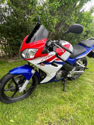 Honda CBR 125R sportbike azul, roja y blanca