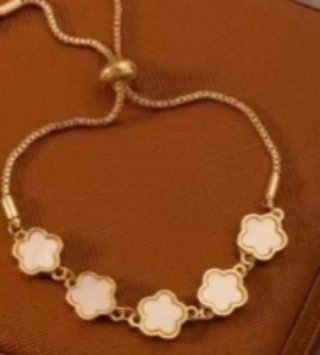 Pulsera dorada con flores blancas
