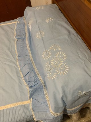 Ropa de cama azul con bordado blanco