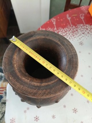 Jarrón de madera oscuro con detalles metálicos.