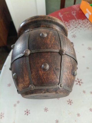 Jarrón de madera oscuro con detalles metálicos.