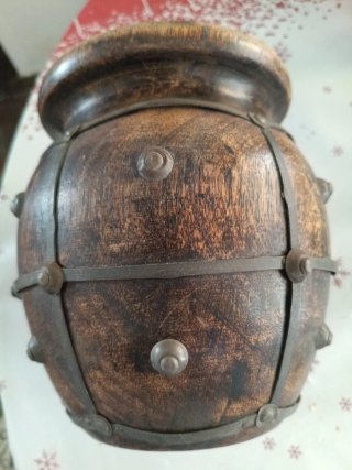 Jarrón de madera oscuro con detalles metálicos.