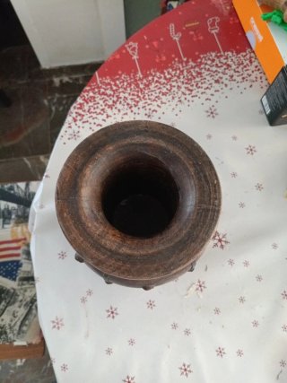 Jarrón de madera oscuro con detalles metálicos.