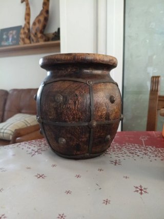 Jarrón de madera oscuro con detalles metálicos.