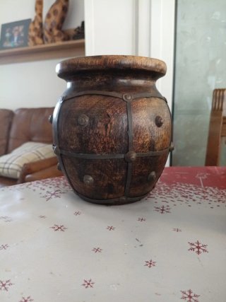 Jarrón de madera oscuro con detalles metálicos.