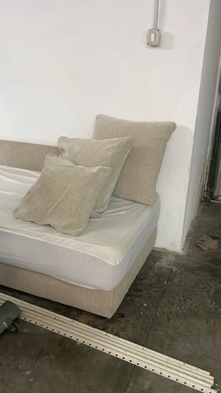 Cama individual beige con colchón y otros muebles