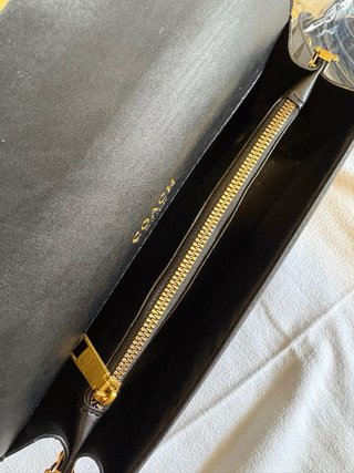 Mala Coach preta com detalhe dourado