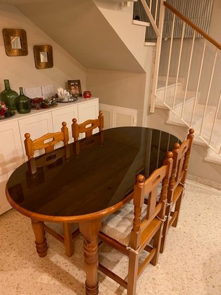 Mesa de salón con vidrio y sillas.