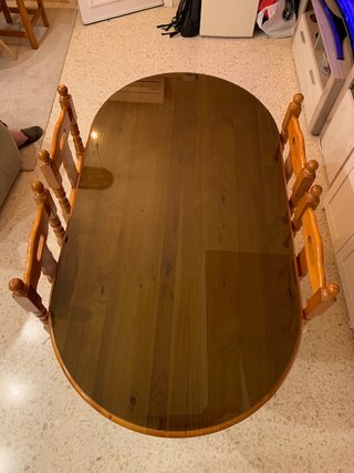 Mesa de salón con vidrio y sillas.