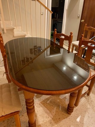 Mesa de salón con vidrio y sillas.