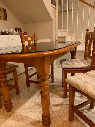 Mesa de salón con vidrio y sillas.