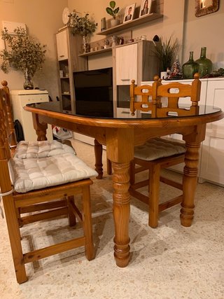 Mesa de salón con vidrio y sillas.