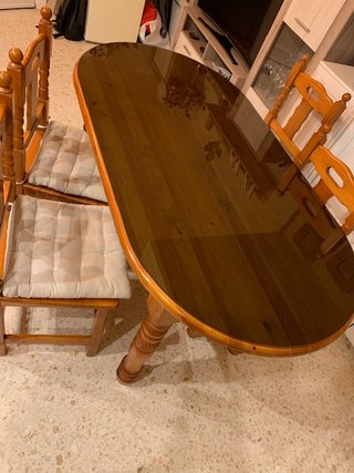 Mesa de salón con vidrio y sillas.