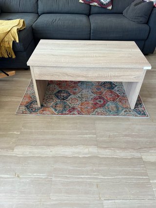 Mesa de centro de madera clara y alfombra.