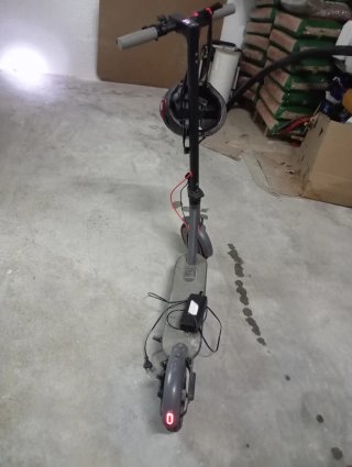 Patinete eléctrico gris, con casco y cargador