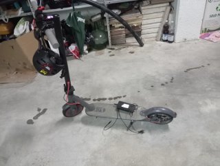 Patinete eléctrico gris, con casco y cargador
