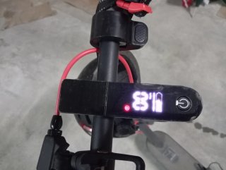 Patinete eléctrico gris, con casco y cargador