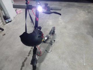 Patinete eléctrico gris, con casco y cargador