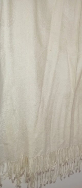 Pañuelo blanco roto con flecos.