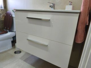 Mueble baño suspendido con lavabo, grifo y espejo.