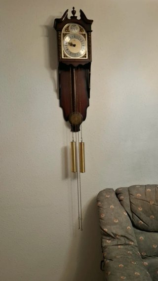 Reloj de pared de madera con péndulo y pesas.