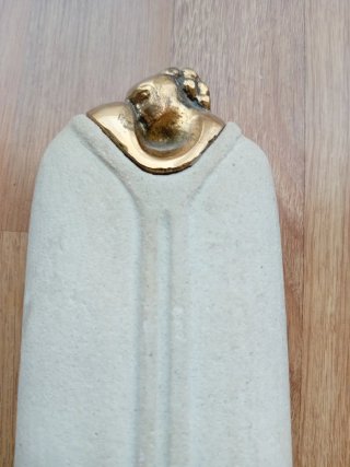 Escultura de piedra beige con base dorada