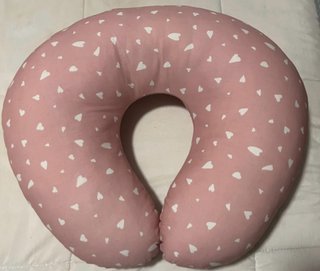 Cojín de lactancia rosa con corazones.