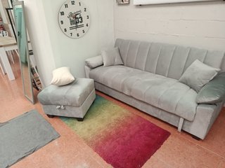 Sofá cama gris con arcón y puff