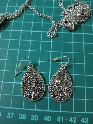 Colgante y pendientes plateados con pedrería