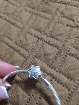 Pulsera Pandora con charm de flor en plata.