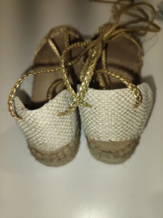 Sandalias doradas con cordones.