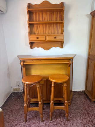 Barra de bar de madera con estantería y taburetes