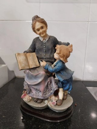 Figura de abuela leyendo a niño.